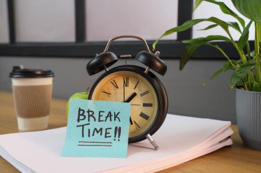 Alarm saati ve yapışkan notla yazılan kırık saat ve masadaki kağıt kağıtlar