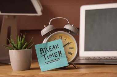 Çalar saat ve yapışkan not. Ofisteki masada mesajlaşma zamanı.