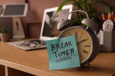 Çalar saat ve yapışkan not. Ofisteki masada mesajlaşma zamanı.