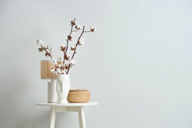 Pamuk çiçekli vazo, hasır kutu ve lamba oturma odasında, yakın plan.