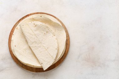 Beyaz zemin üzerinde taze lavaş bulunan ahşap bir tabak.