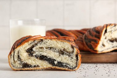 Tatlı haşhaş tohumu rulosu ve beyaz masada bir bardak taze süt.