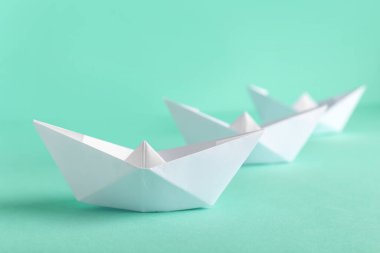Turkuaz arka planda beyaz kağıt tekneler