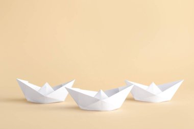Bej arka planda beyaz kağıt tekneler