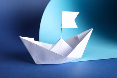 Mavi arka planda bayrağı olan beyaz kağıt tekne