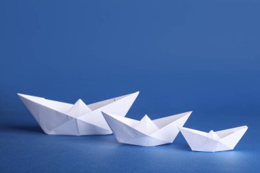 Mavi arka planda beyaz kağıt tekneler