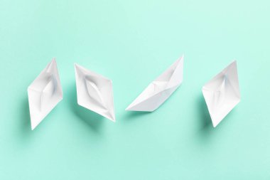 Turkuaz arka planda beyaz kağıt tekneler