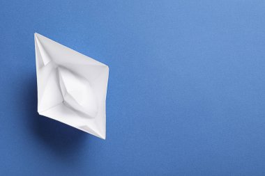 Mavi arka planda beyaz kağıt tekne