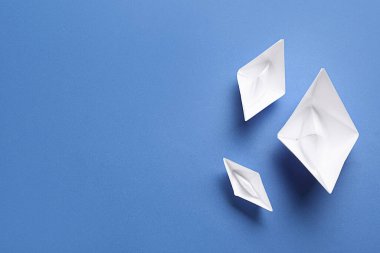 Mavi arka planda beyaz kağıt tekneler