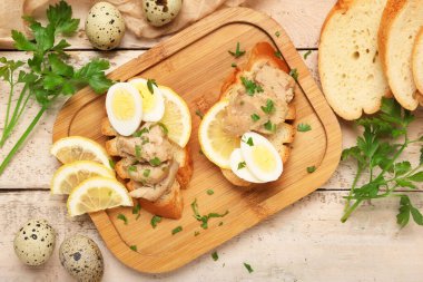 Morina ciğeri, limon ve bıldırcın yumurtası beyaz ahşap arka planda lezzetli sandviçler.