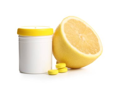 C vitamini haplı bir şişe ve beyaz arka planda yarım limon.