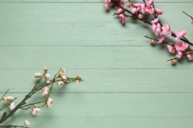 Yeşil ahşap zemin üzerinde çiçek açan güzel dallardan yapılmış çerçeve