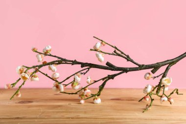 Pembe duvarın yakınındaki ahşap masada güzel dallar, yakın plan.