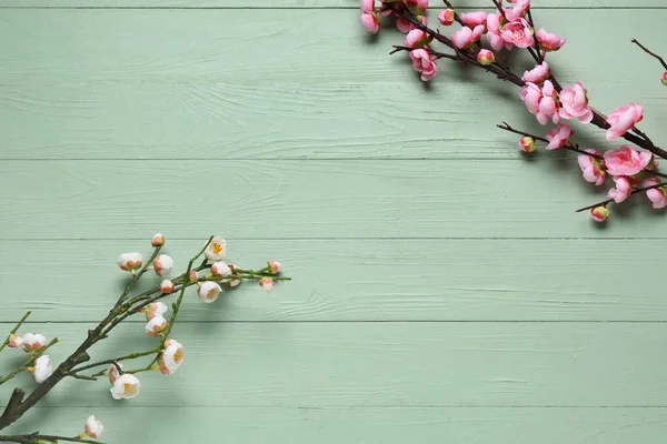 Yeşil ahşap zemin üzerinde çiçek açan güzel dallardan yapılmış çerçeve