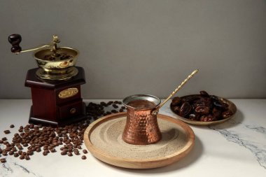 Kum ve tabakta sıcak Türk kahvesi ve beyaz arka planda kurutulmuş hurma.