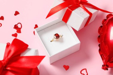 Nişan yüzüğü, hediye kutusu ve pembe arka planda hava balonu. Sevgililer Günü kutlaması