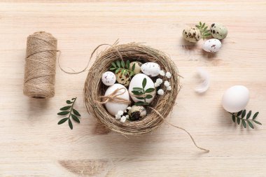 Paskalya yumurtaları, yapraklar ve ahşap arka planda güzel çigila çiçekleri olan yuva.