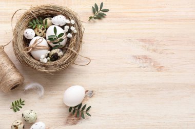 Paskalya yumurtaları, yapraklar ve ahşap arka planda güzel çigila çiçekleri olan yuva.