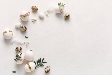 Yaprakları, tüyleri ve beyaz arka planda güzel çigila çiçekleri olan Paskalya yumurtaları.