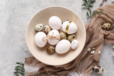 Paskalya yumurtaları, yapraklar ve gri arka planda güzel çigila çiçekleri.