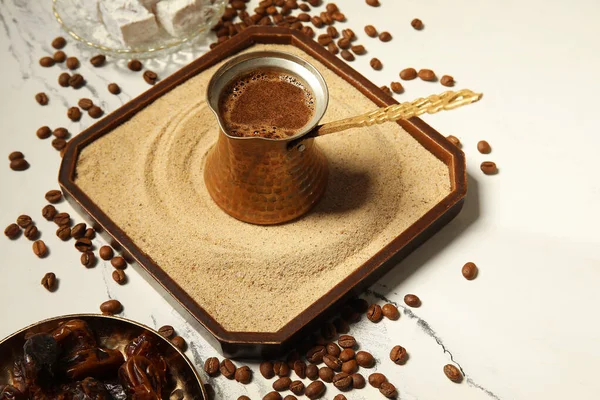Kum ve tabakta sıcak Türk kahvesi, beyaz arka planda kurumuş hurma, yakın plan.