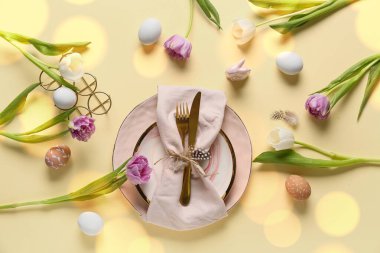 Sarı arka planda Paskalya yumurtaları ve laleleri olan masa ayarı