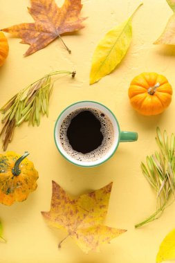 Renkli arka planda bir fincan aromatik kahve, balkabağı ve düşmüş yapraklı kompozisyon