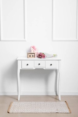 Uluslararası Kadınlar Günü 'nün tarihiyle takvim, laleler ve hediyeler ışık duvarının yanındaki masada.