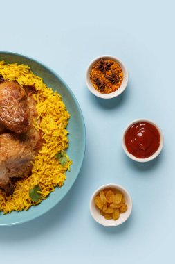 Mavi arka planda baharatlı geleneksel tavuk biryani kasesi.