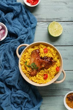 Mavi ahşap arka planda malzemeleri olan bir kase geleneksel tavuk biryani.