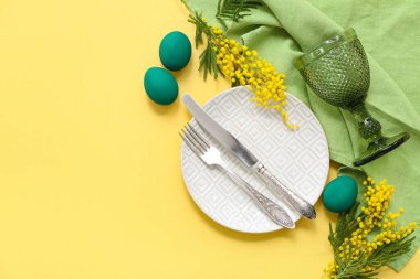 Renkli yumurtalar, yeşil peçete ve sarı arka planda mimoza ile güzel bir Paskalya sofrası.