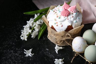 Tatlı Paskalya pastası ve güzel çiçekler, siyah arka planda yumurtaları olan tutucu.