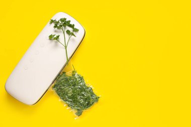 Sarı arka planda maydanozlu yiyecek için vakum mühür makinesi.