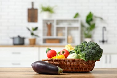 Tahta mutfak tezgahında farklı taze sebzelerle dolu bir sepet.