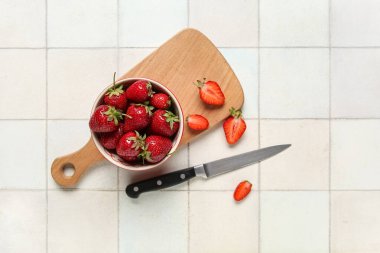 Beyaz fayanslı taze çilekli kase ve ahşap tahta.