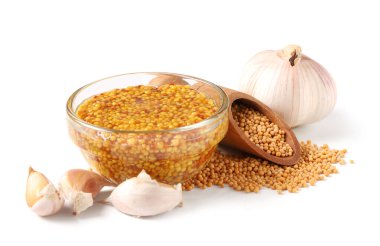 Cam kâse dolusu sarımsaklı Dijon hardalı ve beyaz arka planda tohumlar.