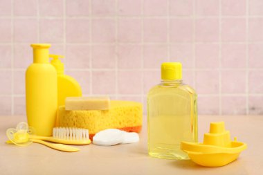 Bej masadaki çocuklar için tekne oyuncağı ve bir şişe kozmetik ürünü.