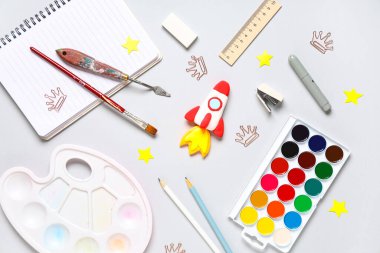 Roket, gri arka planda farklı kırtasiye malzemeleriyle plastikten yapılmış. Üst görünüm