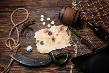 Ahşap arka planda korsan eşyası olan yanmış kağıt.