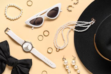 Bej arka planda şapka, fiyonk ve kol saati olan şık aksesuarlar. Yakın çekim.