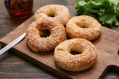 Susam tohumlu lezzetli simit ve ahşap zemin üzerinde taze marul kesme tahtası.