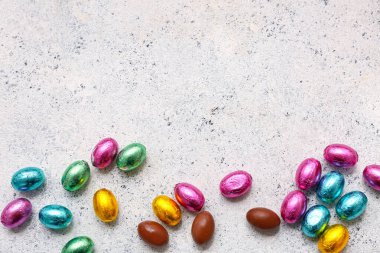 Paketlenmemiş ve paketlenmemiş paskalya yumurtaları hafif grunge arka planda folyoya konmuş.