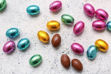 Paketlenmemiş ve paketlenmemiş paskalya yumurtaları hafif grunge arka planda folyoya konmuş.