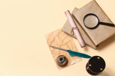 Kitaplı eski kağıt çarşaf, tükenmez kalem, mürekkep hokkası, parşömen ve bej arka planda büyüteç