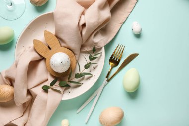 Paskalya yumurtaları ve turkuaz arka planda okaliptüs dallarıyla güzel bir masa.