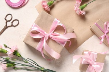 Pembe karanfilli hediye kutuları, bej grunge arka planda ambalaj kağıdı ve makas. Uluslararası Kadınlar Günü