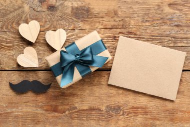 Boş tebrik kartı, hediye kutusu, kalpler ve tahta arka planda kağıt bıyık. Babalar günü kutlaması.