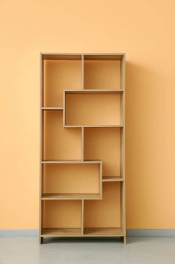 Sarı duvarın yanındaki boş ahşap raf ünitesi.