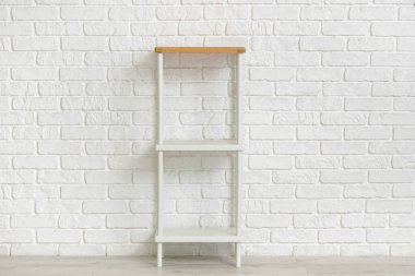 Beyaz tuğla duvarın yanındaki boş raf ünitesi