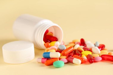 Açık sarı arka planda haplı şişe